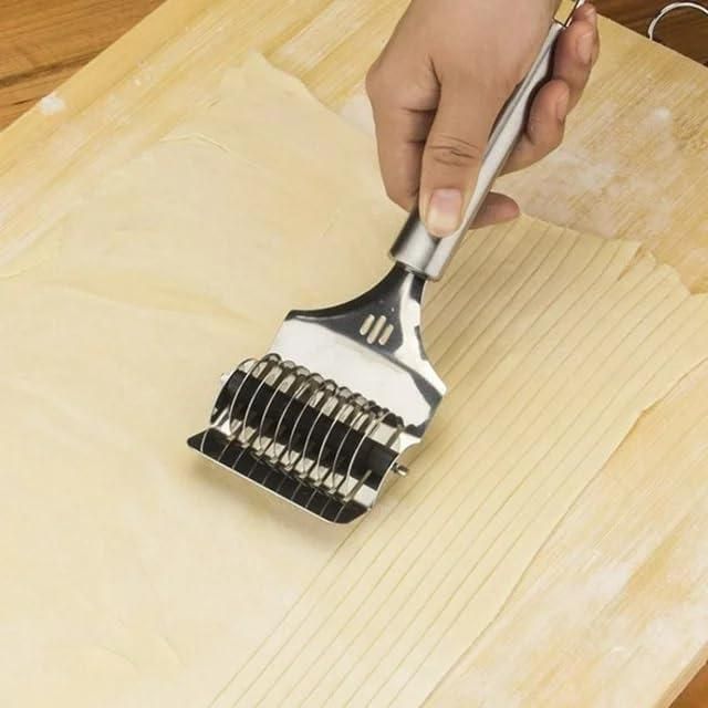 Stainless steel handheld dough and manual noodle cutter tool by 1h8x0d-zb on a wooden surface with fresh pasta.
