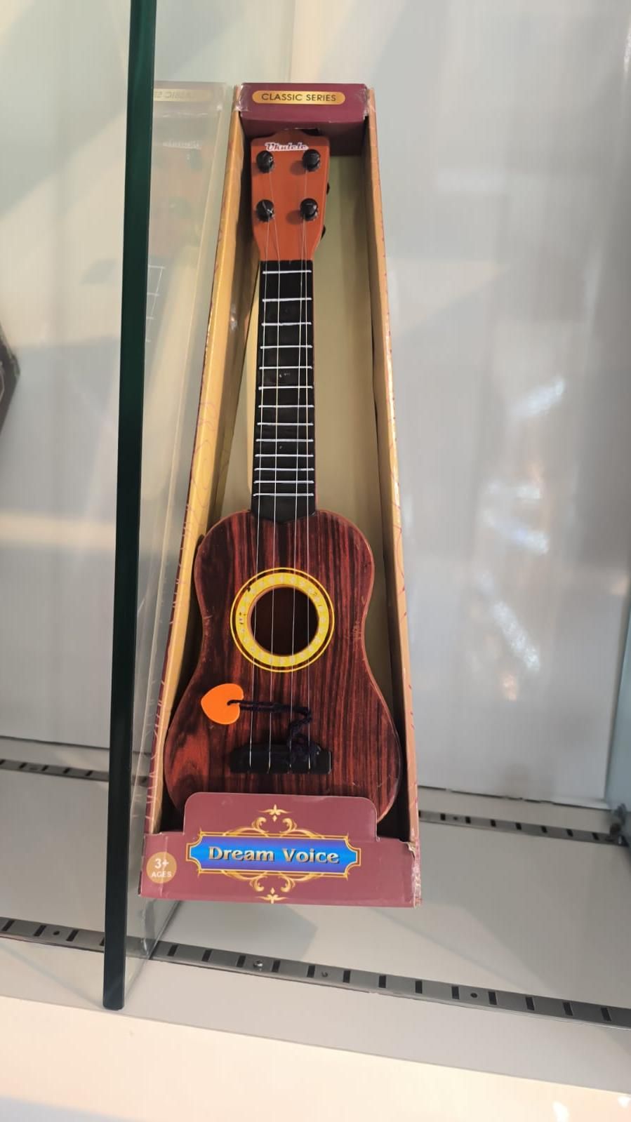 Mini wooden finish plastic guitar by 1h8x0d-zb with 4 strings, showcasing its clear sound and detailed design.